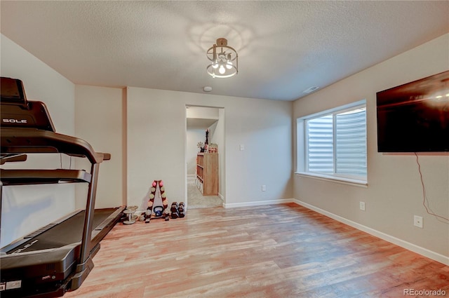 exercise area featuring visible vents, baseboards, a notable chandelier, a textured ceiling, and wood finished floors