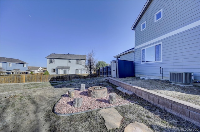 view of yard featuring an outdoor fire pit, central AC unit, and fence