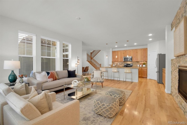 living area with light wood-style floors, a fireplace, recessed lighting, and stairway