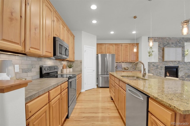 kitchen featuring stainless steel appliances, a sink, light wood-style floors, tasteful backsplash, and recessed lighting