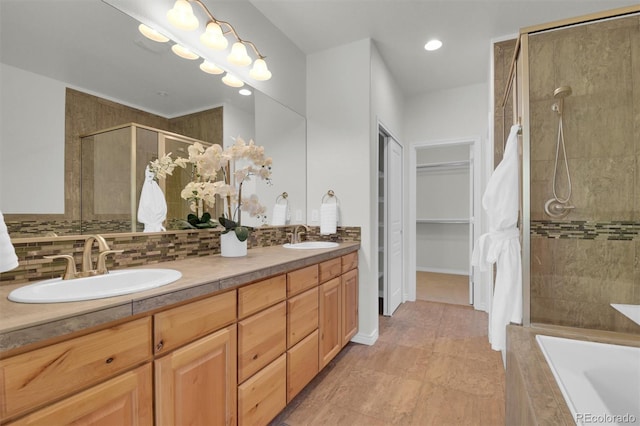 full bathroom featuring a tile shower, backsplash, double vanity, tiled tub, and a spacious closet