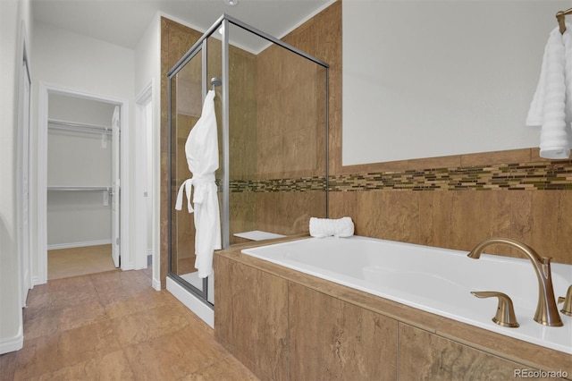bathroom featuring a shower stall, a walk in closet, and a bath