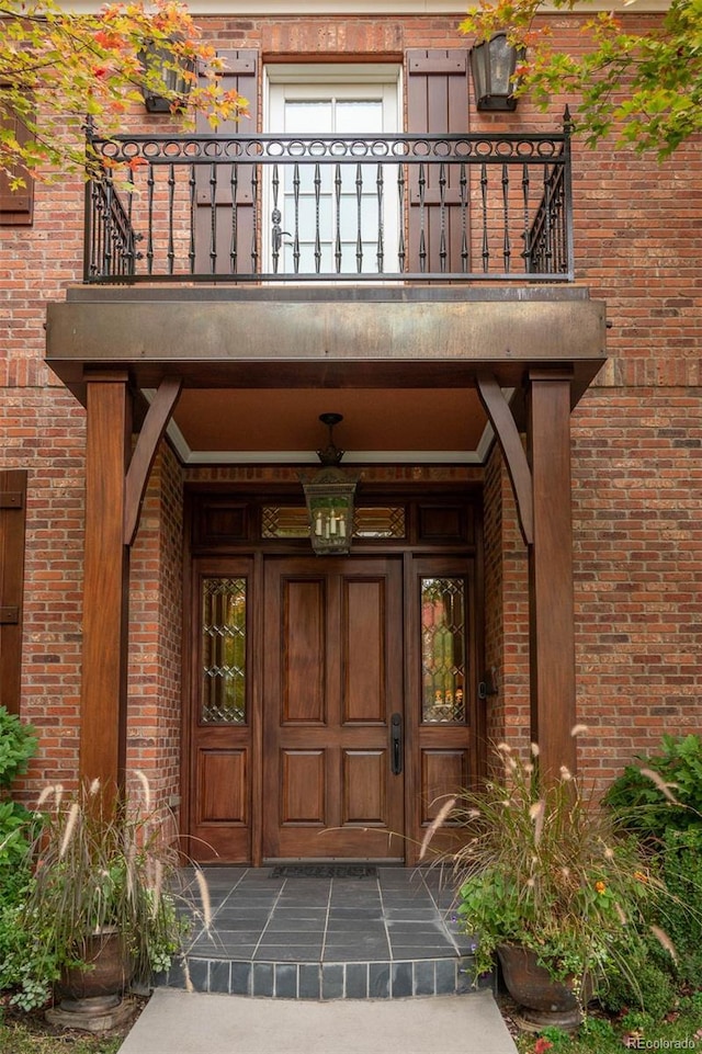 property entrance featuring a balcony and brick siding