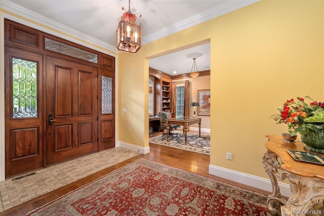 foyer entrance featuring a notable chandelier, crown molding, baseboards, and wood finished floors