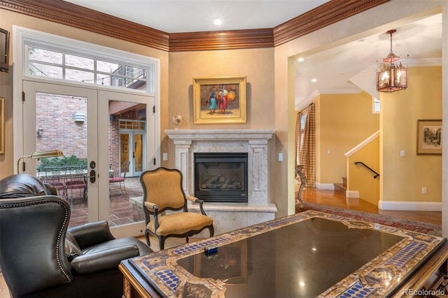 living room with a fireplace, wood finished floors, stairs, french doors, and ornamental molding