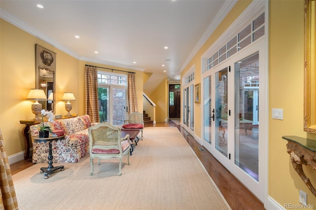 sitting room with light wood-style floors, french doors, crown molding, and baseboards