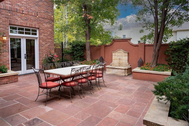 view of patio with outdoor dining space, french doors, and fence