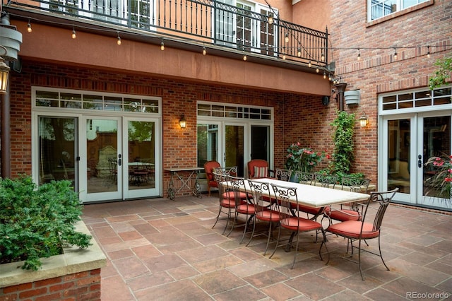 view of patio with french doors, outdoor dining space, and a balcony