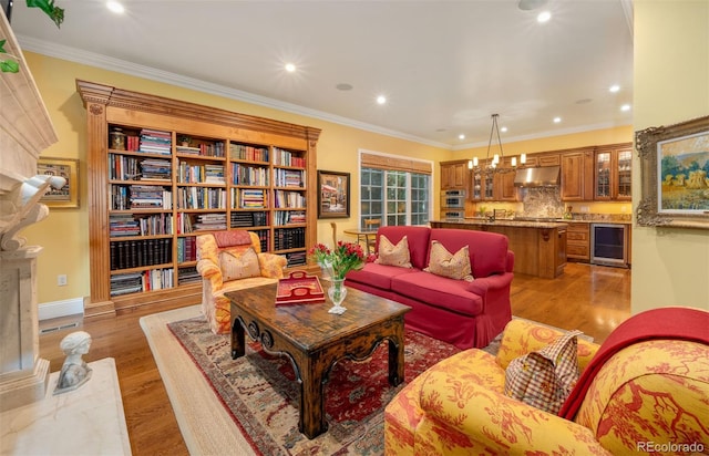 living room featuring wine cooler, recessed lighting, a high end fireplace, ornamental molding, and light wood finished floors