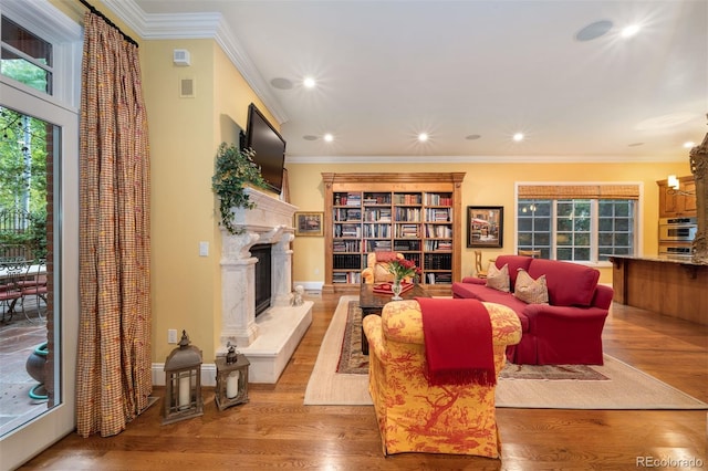 living area with a chandelier, a premium fireplace, wood finished floors, and crown molding