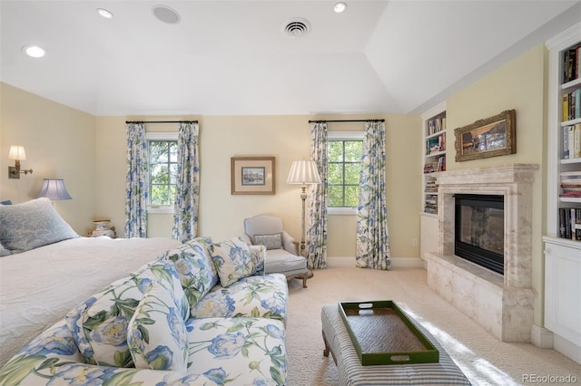 bedroom with light carpet, multiple windows, a fireplace, and visible vents