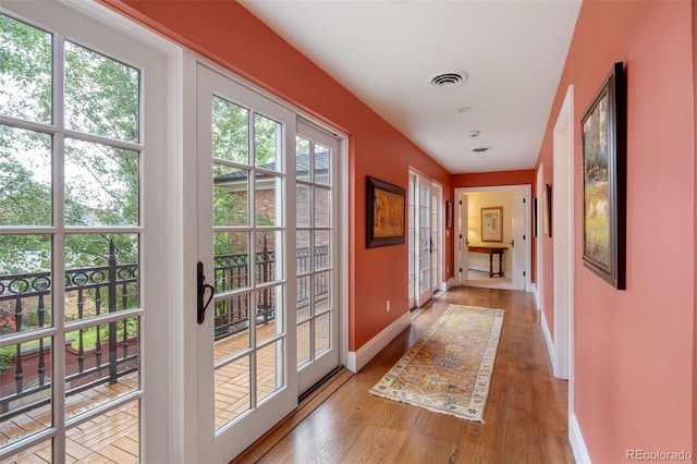 doorway with light wood-type flooring, baseboards, and visible vents