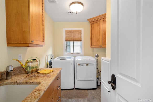 laundry area featuring cabinet space, visible vents, a sink, and washing machine and clothes dryer