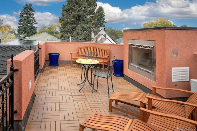 view of patio featuring a water view, a glass covered fireplace, and visible vents