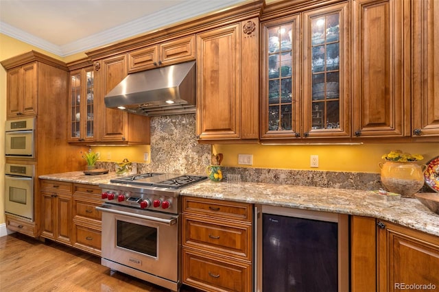 445 Madison St N, Denver, CO 80206 - kitchen featuring ornamental molding, brown cabinets, wine cooler, stainless steel appliances, and under cabinet range hood