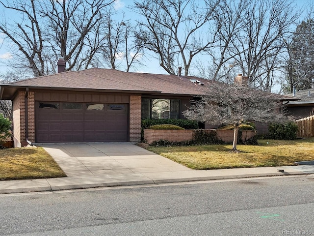 view of front facade featuring a garage, brick siding, driveway, a chimney, and a front yard