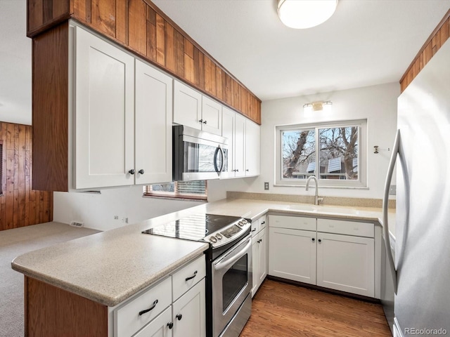 kitchen with white cabinetry, appliances with stainless steel finishes, light countertops, and a sink