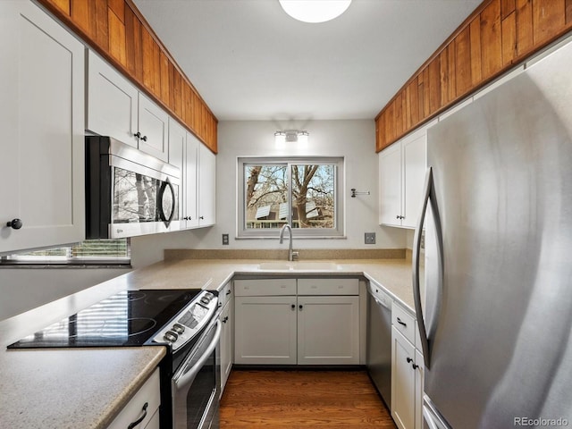 kitchen with dark wood-style flooring, light countertops, appliances with stainless steel finishes, white cabinetry, and a sink