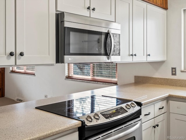 kitchen with appliances with stainless steel finishes, light countertops, and white cabinetry