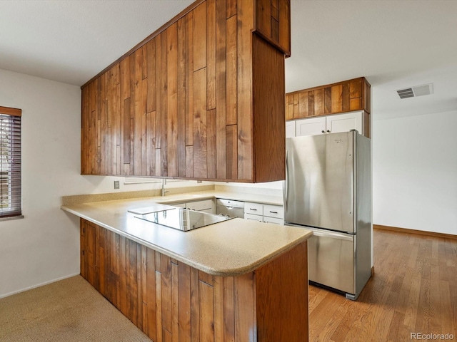 kitchen featuring visible vents, appliances with stainless steel finishes, a peninsula, light countertops, and white cabinetry