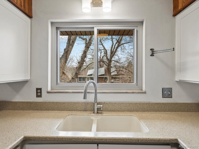 kitchen featuring a sink, light stone countertops, and white cabinets