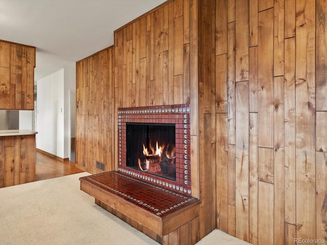 interior details with carpet floors, wood walls, and a lit fireplace