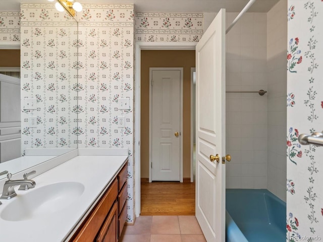 bathroom with tile patterned floors, shower / bath combination, vanity, and wallpapered walls