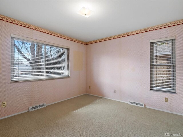 carpeted empty room featuring baseboards and visible vents