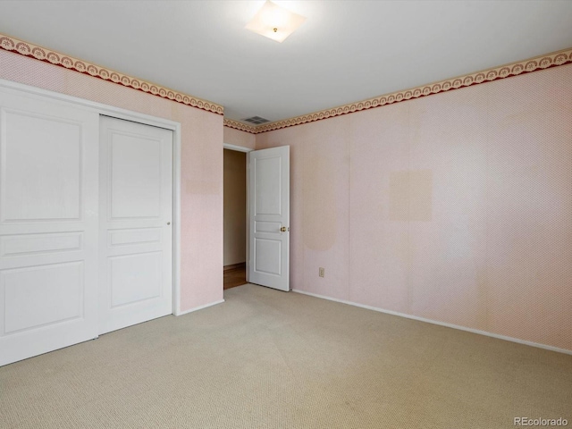 unfurnished bedroom featuring visible vents, a closet, and light colored carpet