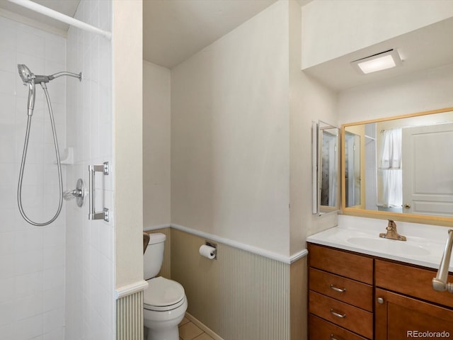 full bath with a wainscoted wall, a tile shower, and toilet