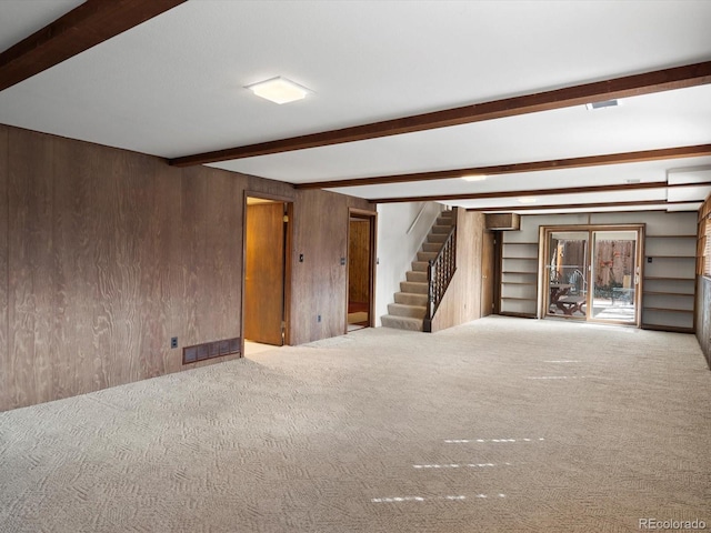 below grade area featuring carpet floors, wood walls, and stairs