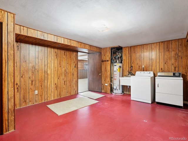 finished basement featuring washer and dryer, gas water heater, and wooden walls