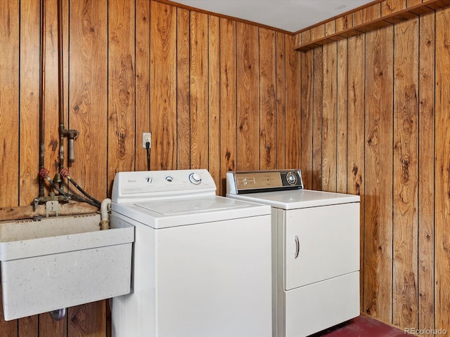 laundry room with laundry area, wood walls, a sink, and washer and dryer