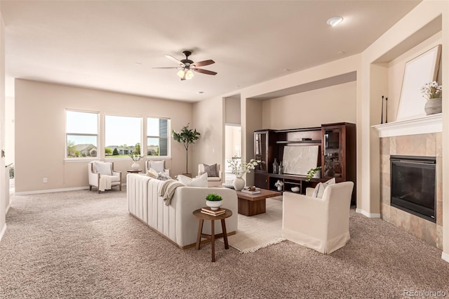 living room featuring baseboards, ceiling fan, carpet flooring, and a tile fireplace