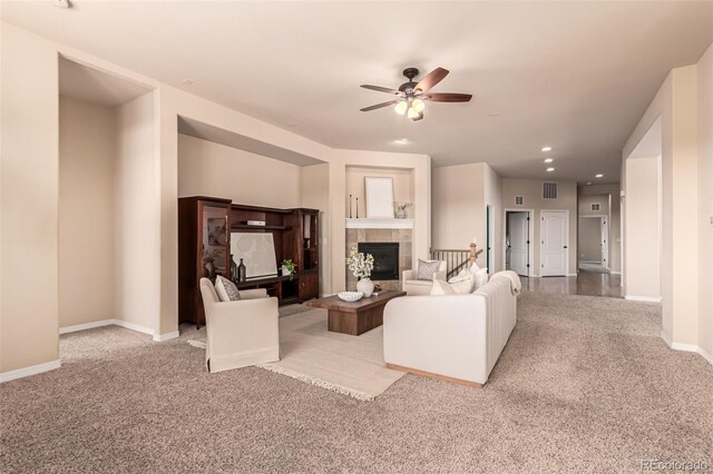 living room featuring carpet floors, a ceiling fan, visible vents, and a tile fireplace