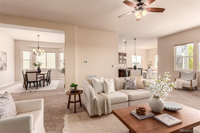 living room with ceiling fan with notable chandelier, carpet flooring, and a wealth of natural light
