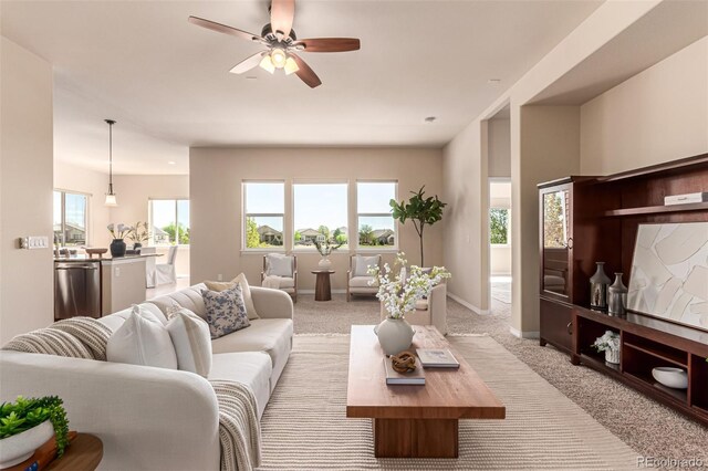 living room with ceiling fan, light carpet, and baseboards