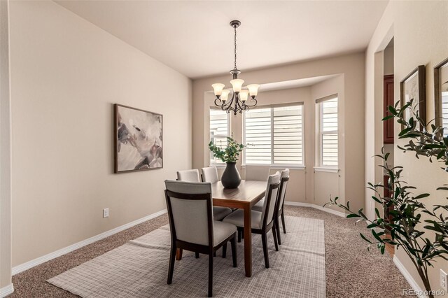 dining space featuring a notable chandelier, light colored carpet, and baseboards