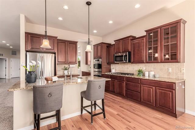 kitchen with visible vents, a kitchen breakfast bar, tasteful backsplash, a sink, and stainless steel appliances