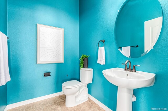 bathroom featuring tile patterned floors, baseboards, and toilet