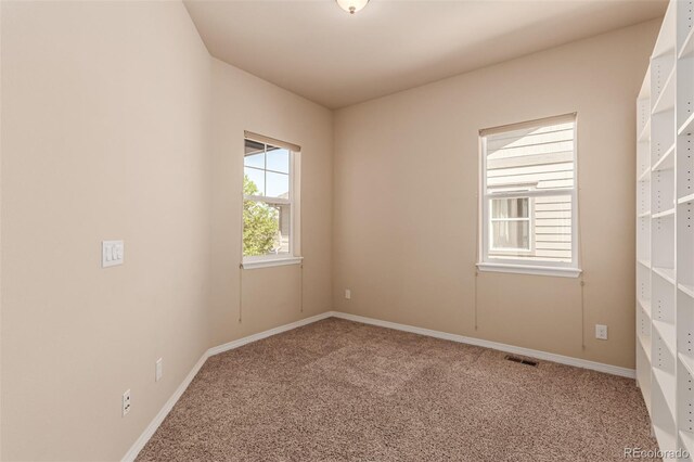 carpeted spare room featuring visible vents and baseboards