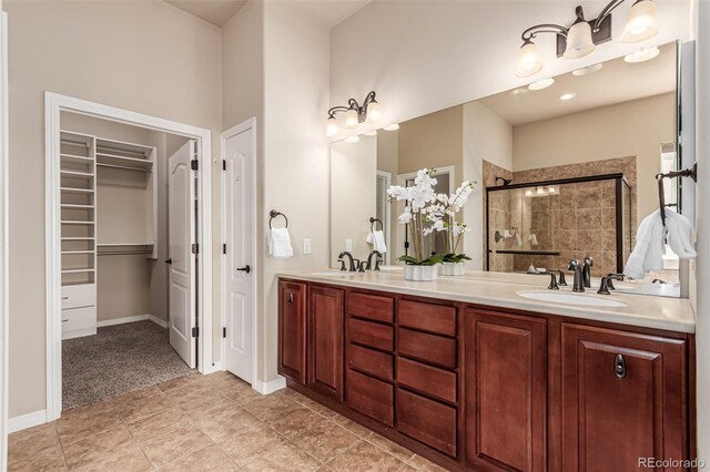 full bathroom with double vanity, a spacious closet, a sink, and a stall shower