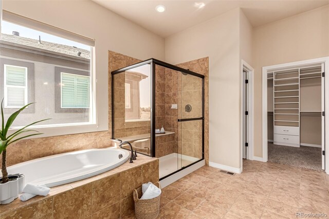 full bathroom with a spacious closet, a shower stall, a bath, and visible vents