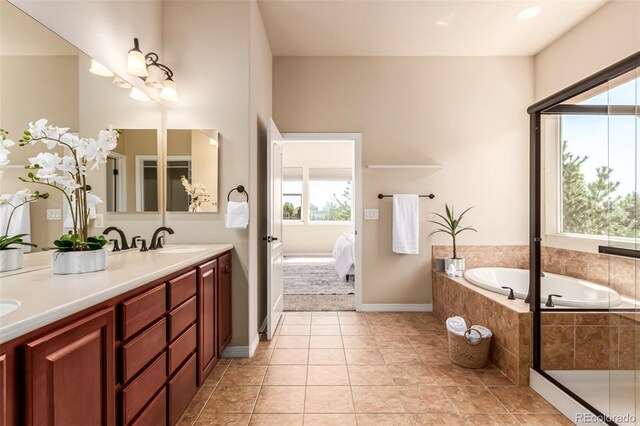 bathroom with a healthy amount of sunlight, ensuite bathroom, a garden tub, and a sink