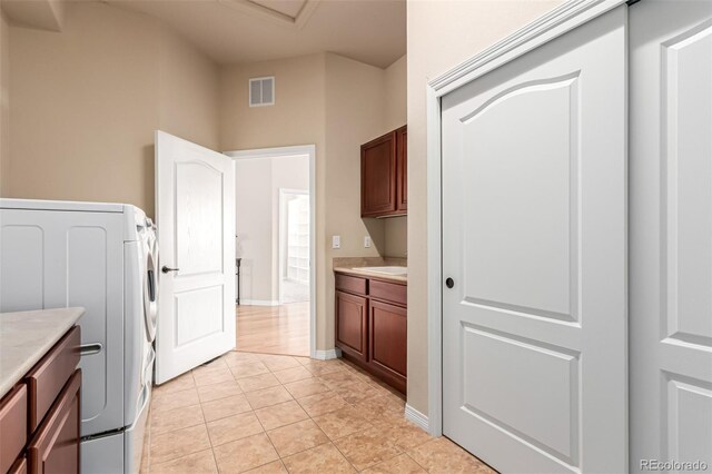 laundry area featuring visible vents, cabinet space, baseboards, washer / dryer, and light tile patterned flooring