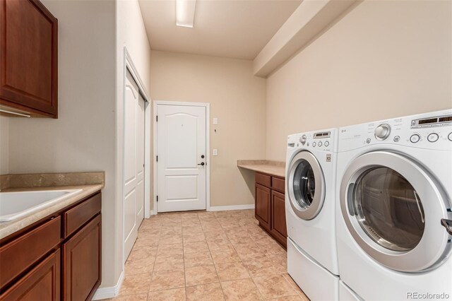 laundry room featuring a sink, baseboards, washing machine and dryer, and cabinet space