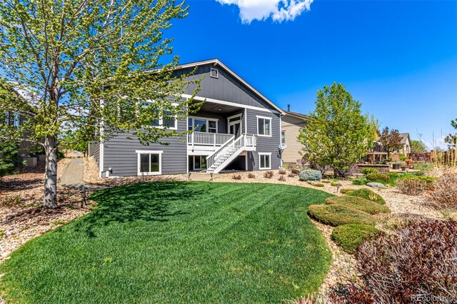 rear view of property featuring a wooden deck, stairs, and a yard