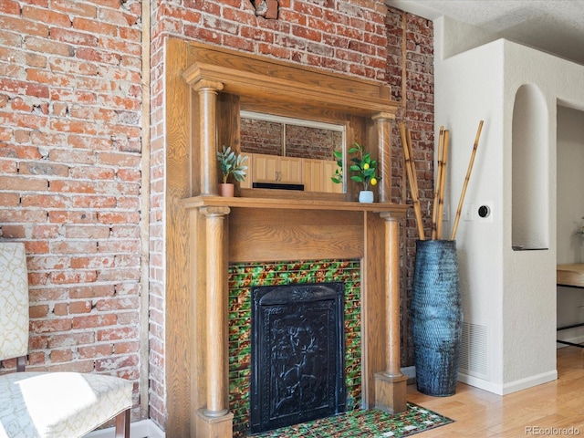 living room featuring a tile fireplace, wood-type flooring, and brick wall