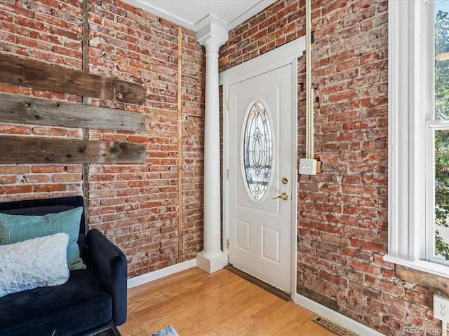 entryway with brick wall and light wood-type flooring