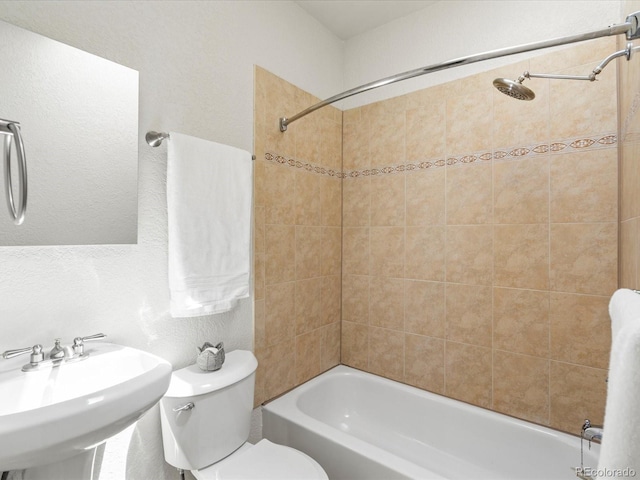 full bathroom with tiled shower / bath combo, toilet, and sink